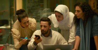 Still image from the film 'The Voice of Hind Rajab' in which several characters, looking frightened, are gathered around a cell phone.
