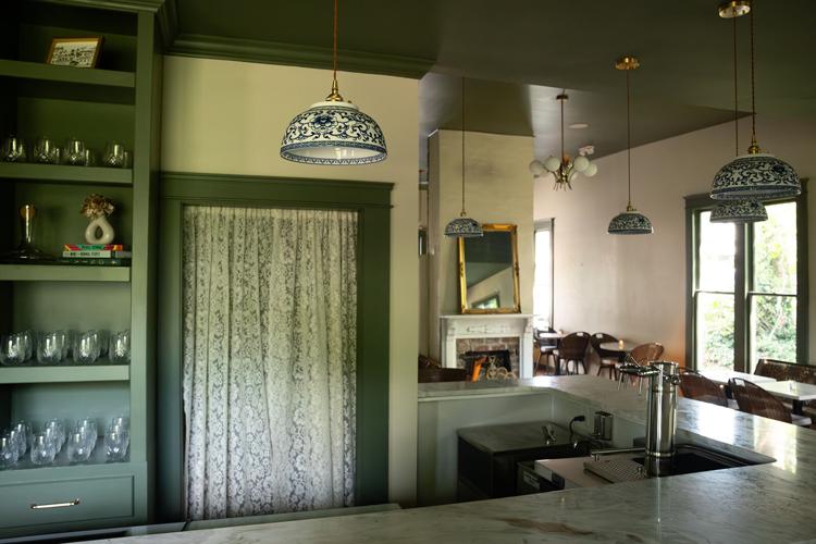 Color photo of the bar area at Antoinette’s Wine + Provisions, with a 90-degree turn at the right leading to an area with more seating by a window