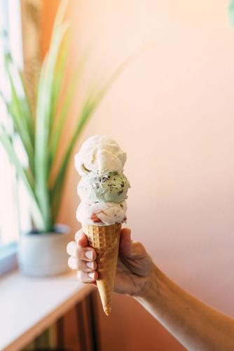 A hand holding a three-scoop cone of ice cream from Koko’s Ice Cream