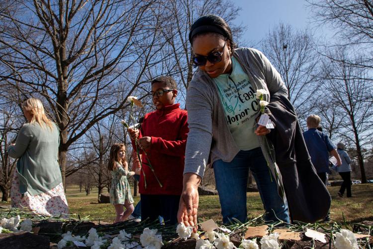 Shawna Metoyer and her son James place flowers on a stone memorial wall in honor of the enslaved people buried at The Hermitage