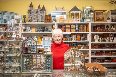 A woman behind a counter displaing miniature homes, with more miniature sets behind her. It's the inside of Miniature Cottage, which is the Nashville Scene’s 2026 Writers’ Choice for Best Small Business in Nashville for their miniature versions of houses, furniture, books, dolls, paintings and more.