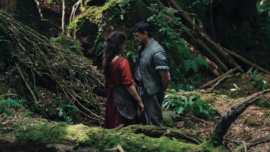 A still from 'Hamnet' with Agnes (Jessie Buckley) and Shakespeare (Paul Mescal) staring at each other in a lush green forest