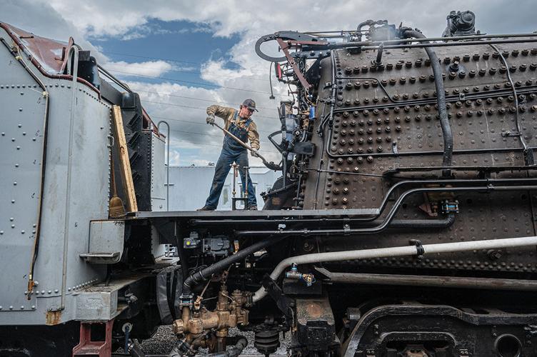 A man shovels coal into the boiler of a train