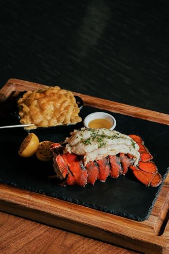 Lobster tail and mac and cheese on a black platter