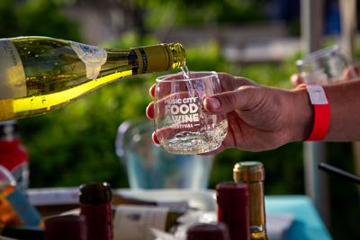 A bottle of wine being poured into a glass that reads "Music City Food and Wine Festival"