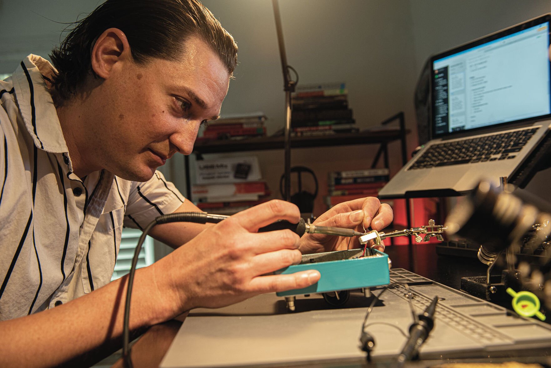 Jesse Rude solders a guitar effects pedal in his workshop