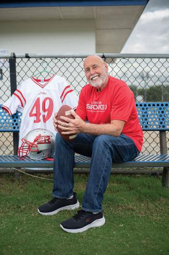 Mike Flynt seated while holding a football