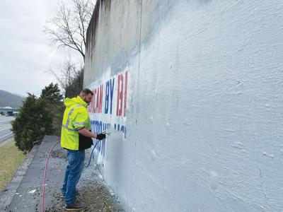 A TDOT employee paints over white supremacist graffiti near I-65, February 2023