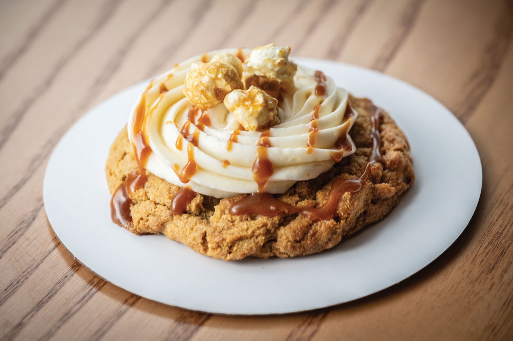 A cookie topped with buttercream and caramel and kettle corn
