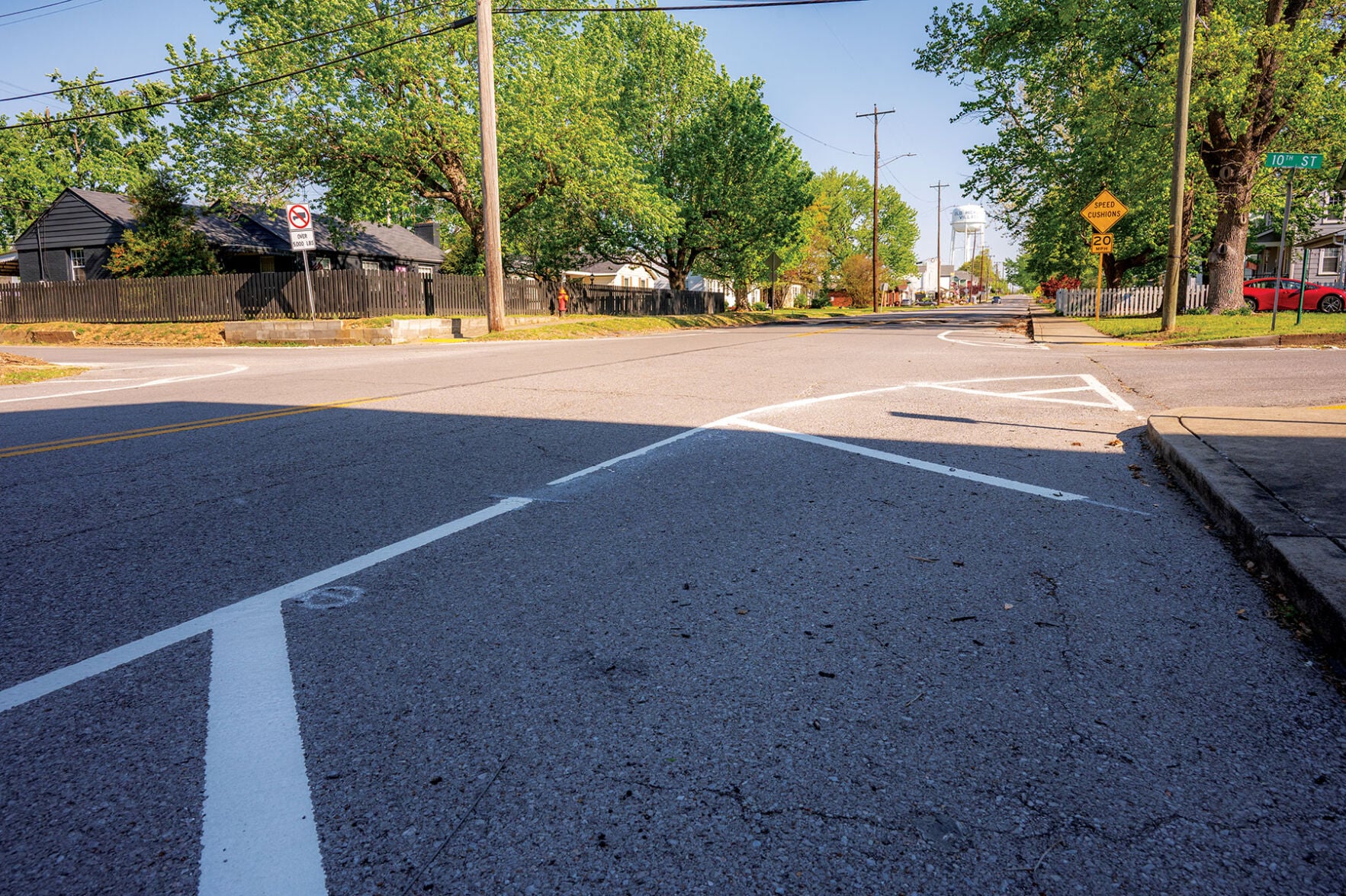 A street with white lines separating traffic from the sidewalk near an intersection.