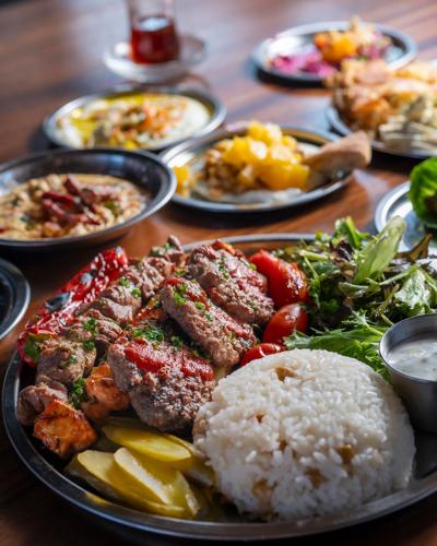 grilled kebabs on a place with rice, lettuce and tomatoes