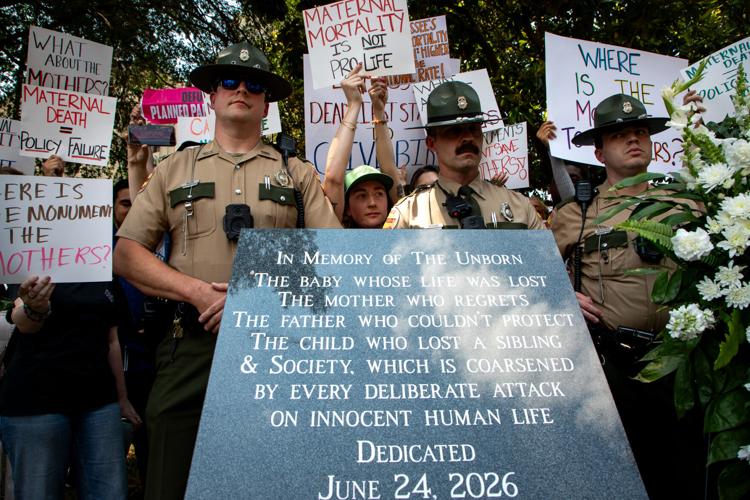State troopers stand between pro-choice protesters and an anti-abortion memorial outside the state Capitol, June 24, 2026