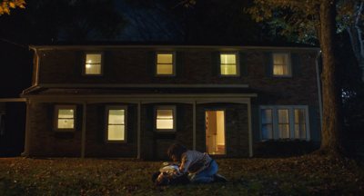 A still from the independent film The Other People, with a house in the background and two characters in the foreground