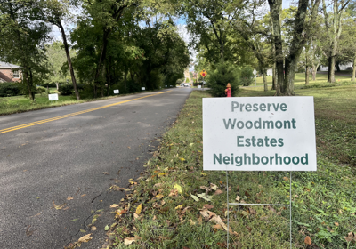 A small roadside sign reading 'Preserve Woodmont Estates Neighborhood'