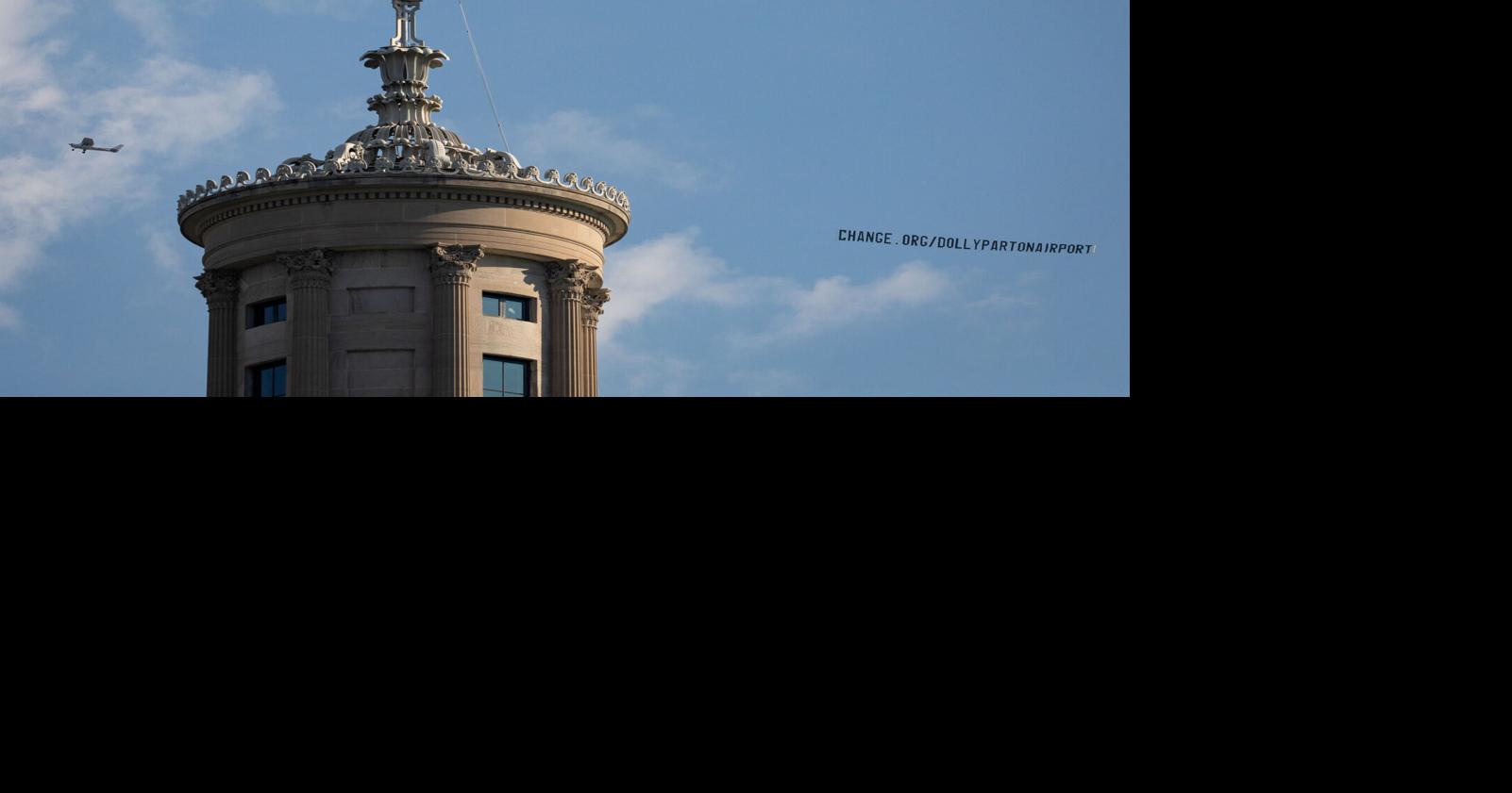 A plane towing a banner promoting a petition to rename the Nashville International Airport in honor of Dolly Parton flies past the state Capitol, Aug. 28