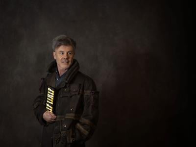 Thomas Dolby press photo artist stands and holds a miniature keyboard