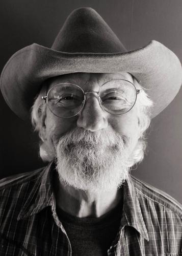 Ray Sisk black and white pic artist wearing cowboy hat smiles into camera