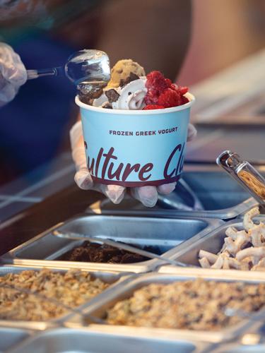 Frozen yogurt and toppings scooped into a blue cup, with part of the "Culture Club" brand name showing.