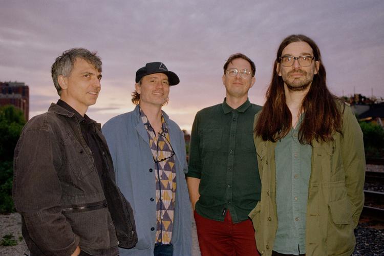 Color photo of the four current members of Canadian electronic rock band Holy Fuck, standing outside at dusk