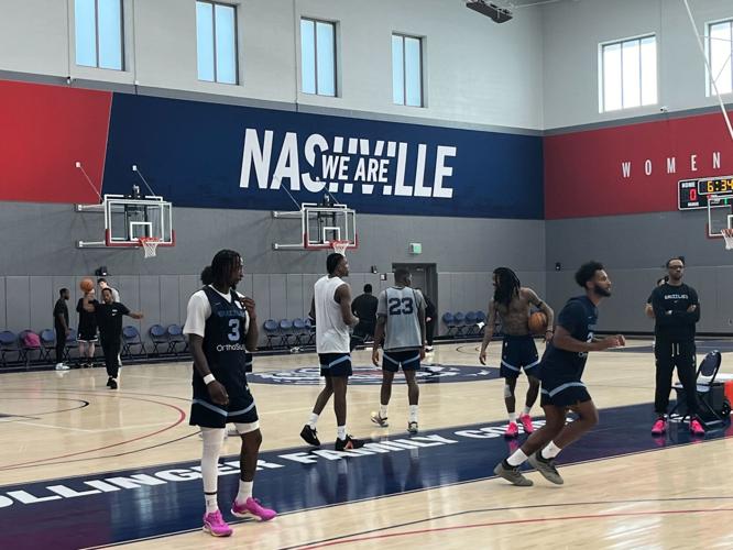 Members of the Memphis Grizzlies practice on a basketball court, with a blue banner reading "We Are Nashville" in the background