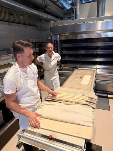 Tyler and Aubrey O'Laskey in white chef's aprons in front of their massive oven