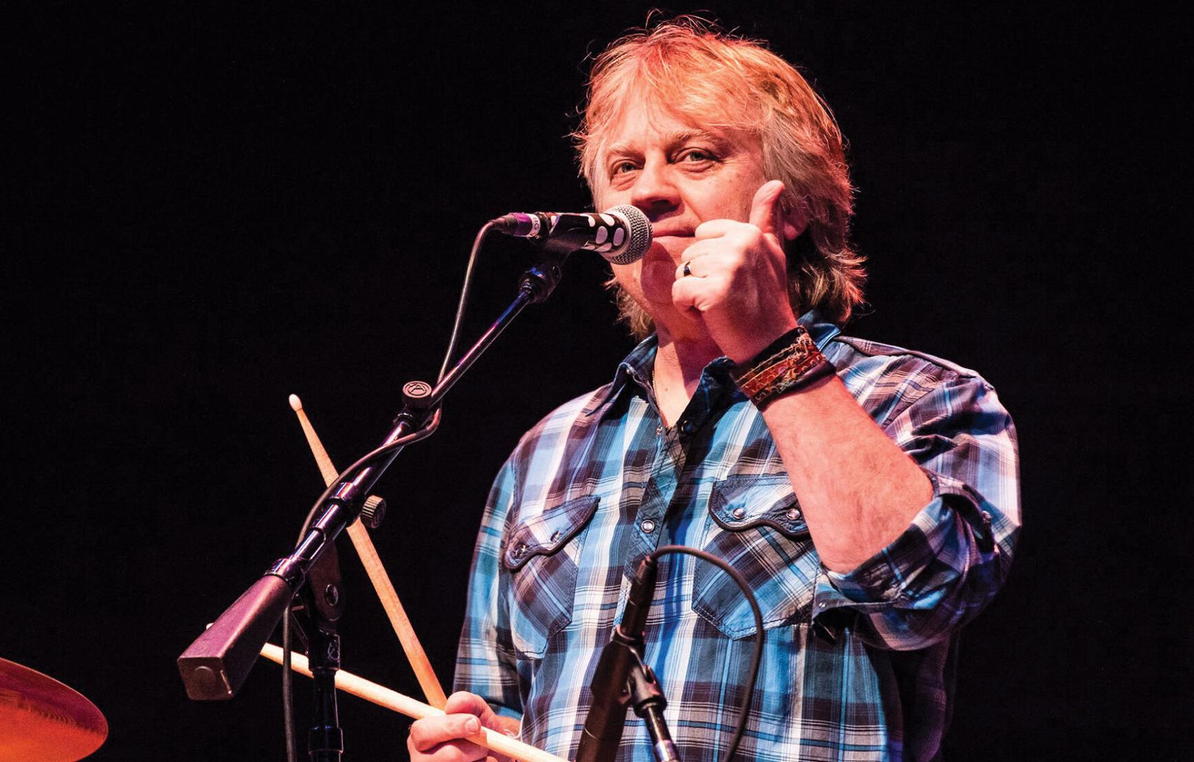 Tom Hambridge onstage standing at a mic and giving a thumbs-up