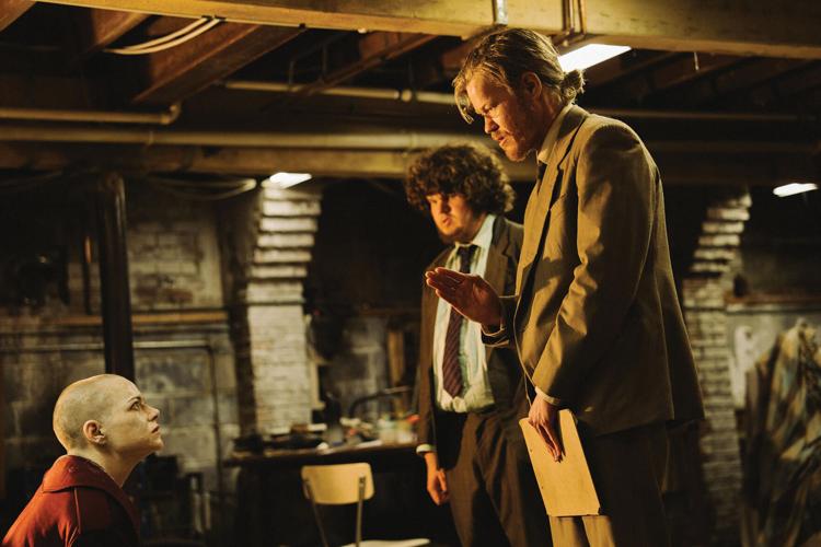 A still from Bugonia with Emma Stone, seated, looking up at Jesse Plemmons.