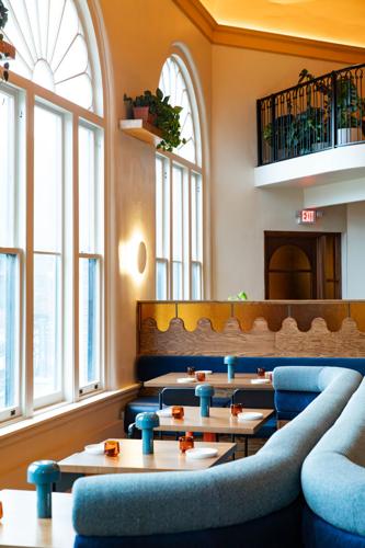 Three tables near a window with a long booth wrapping around the other side
