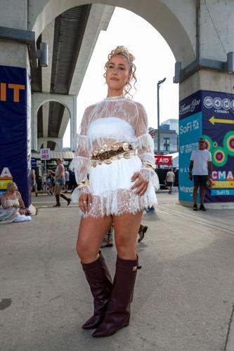 Street fashion color portrait of CMA Fest fan Lexi Nowotarski, highlighting the statement belts on her white Ella Langley-inspired outfit.