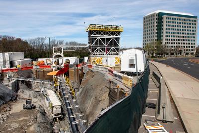 A dig site full of heavy excavation machinery near a city street