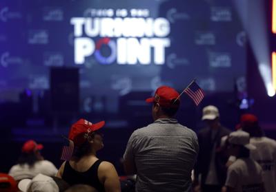 Two attendees at a Turning Point USA event wearing red MAGA caps