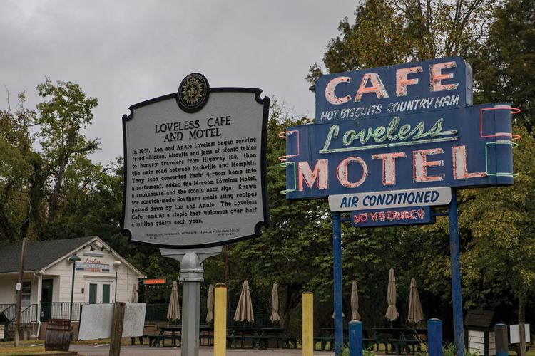 The Loveless Cafe blue and neon sign next to a historical marker commemorating the restaurant.