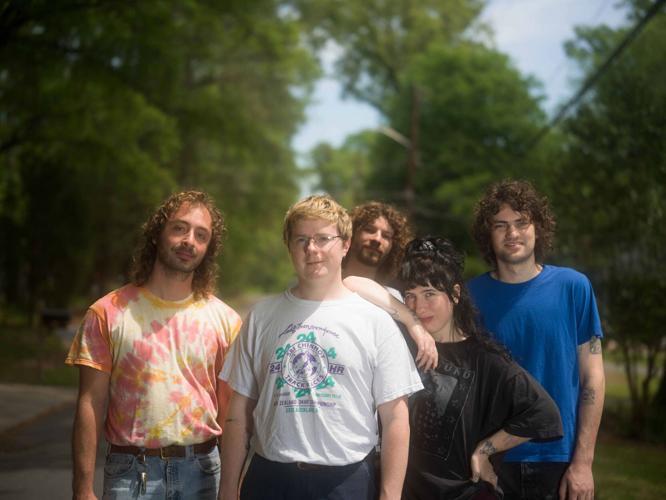 Standing outside in the sun against a backdrop of trees and wearing everyday street clothes, the band stands side by side and smiles into the camera