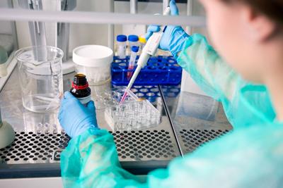 Conducting research work on cancer in laboratory, pipetting samples