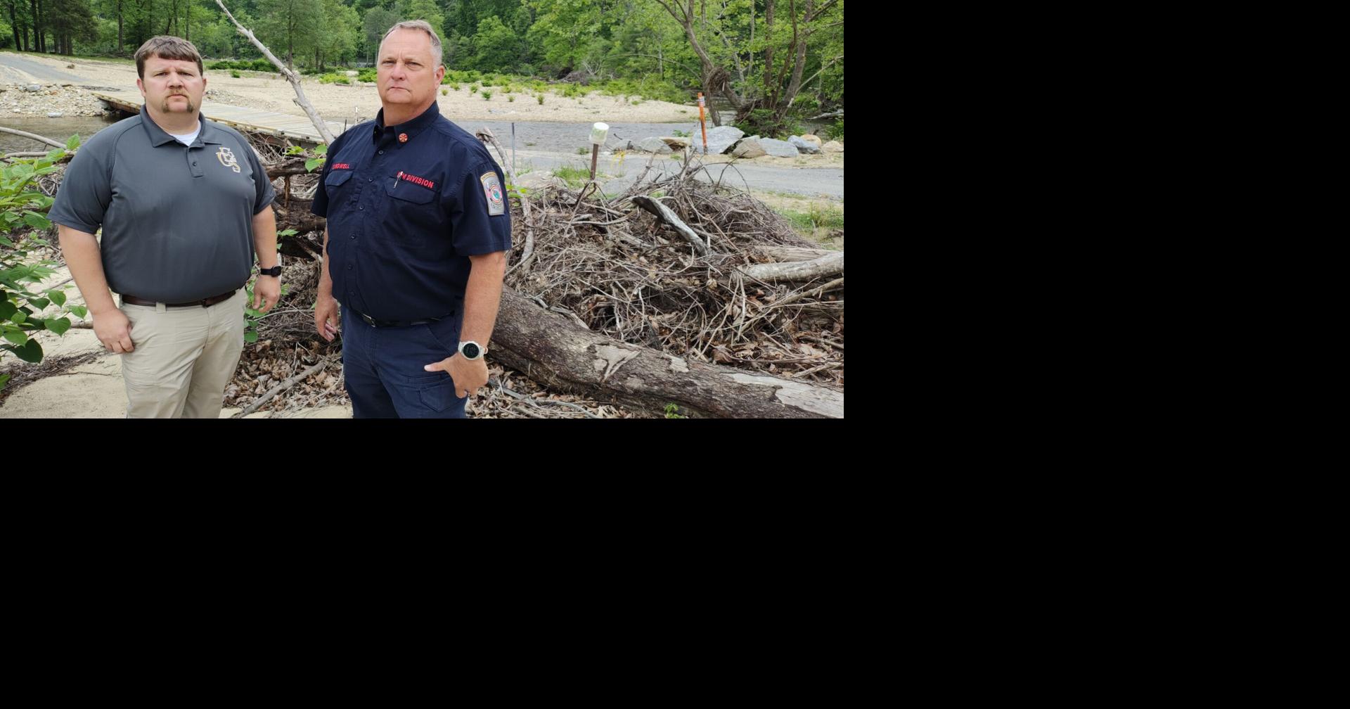 Caldwell County emergency services personnel stand in front of a pile of debris