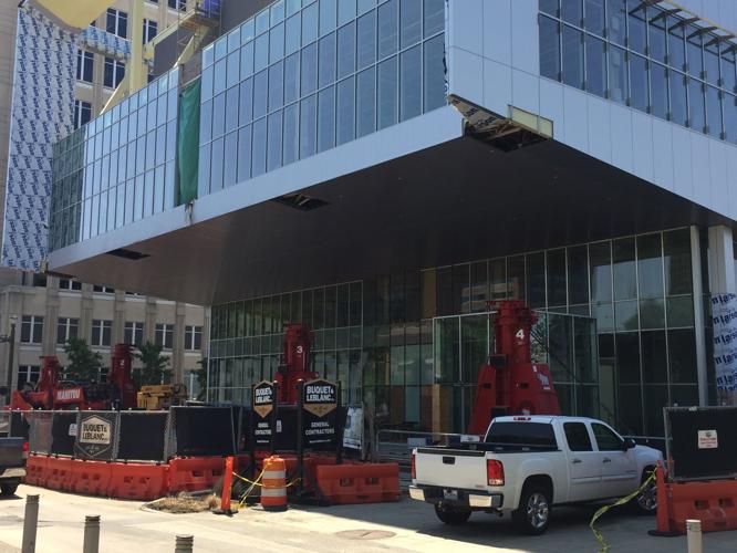 Workers retract hydraulic lifts that had been holding up part of new