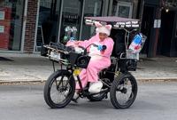 Street performer Mamie Marie Francois pedals up St. Charles Avenue on Good Friday