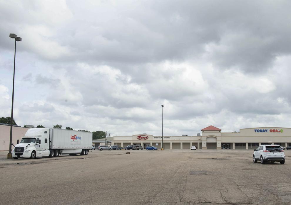 A barren parking lot of a large trip mall under an overcast sky. There is a sign of Rose's Discount Store.