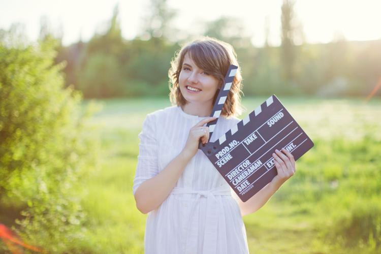 Woman holds clapper board at sunset