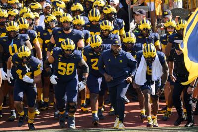 Michigan head coach Sherrone Moore and the Wolverines run out of the tunnel for the start of a game against Wisconsin at Michigan Stadium on Oct. 4, 2025, in Ann Arbor, Michigan.
