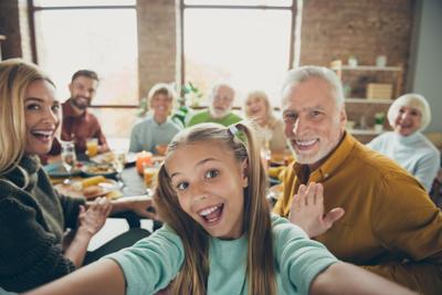 Video call from happy big family celebrate thanksgiving day october autumn event party small little girl kid make selfie mature grandfather say hi wave hand grandmother enjoy meal in house