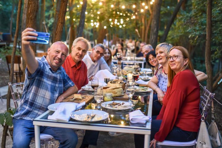 Group of happy people making selfie at the restaurant in the forest environment