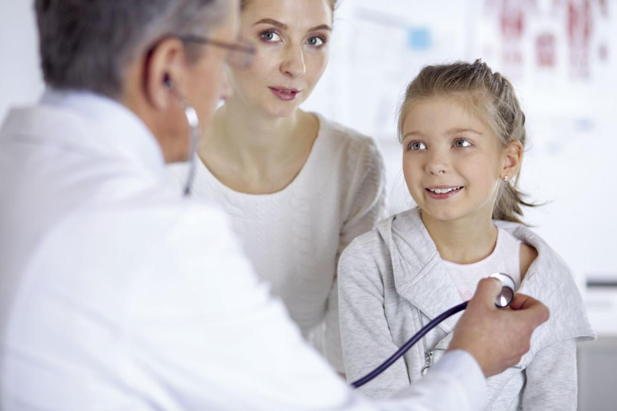 Girl and doctor with stethoscope listening to heartbeat