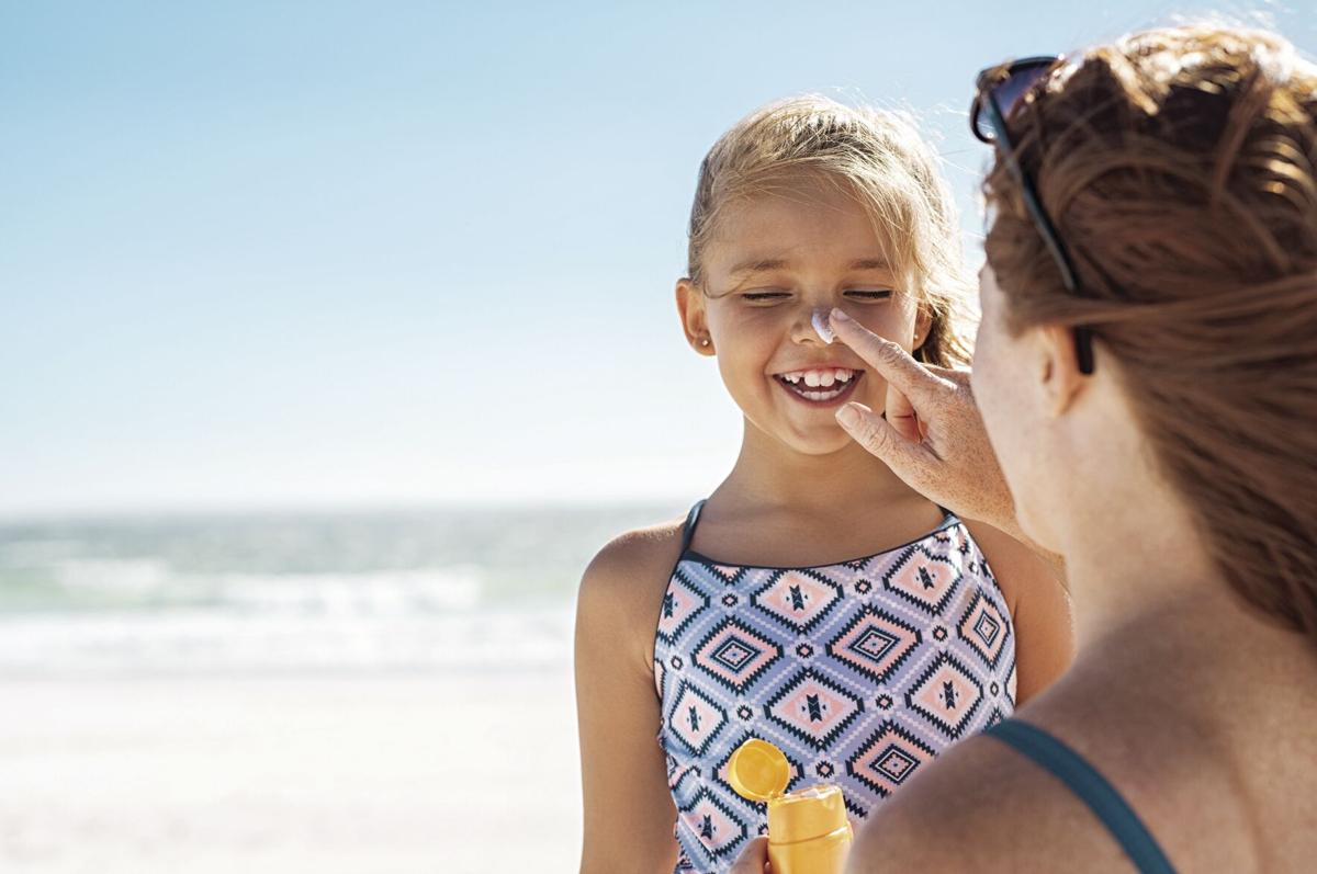 Mother applying suntan lotion on daughter face