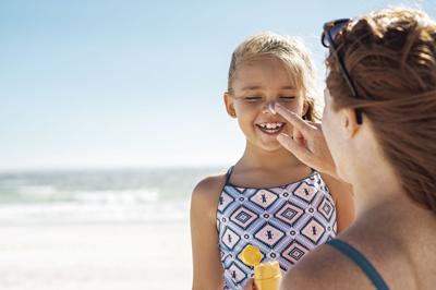 Mother applying suntan lotion on daughter face