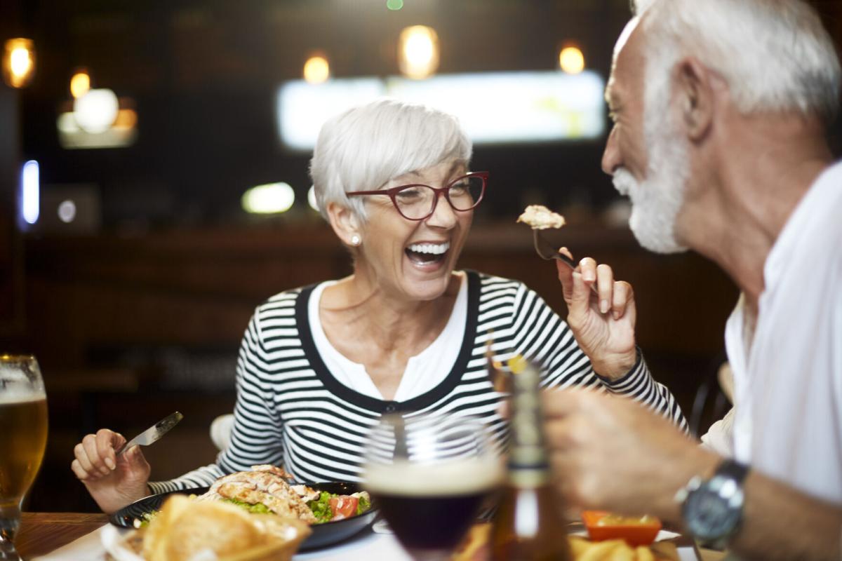 Senior couple feeding each other and having a good time during a meal in a restaurant