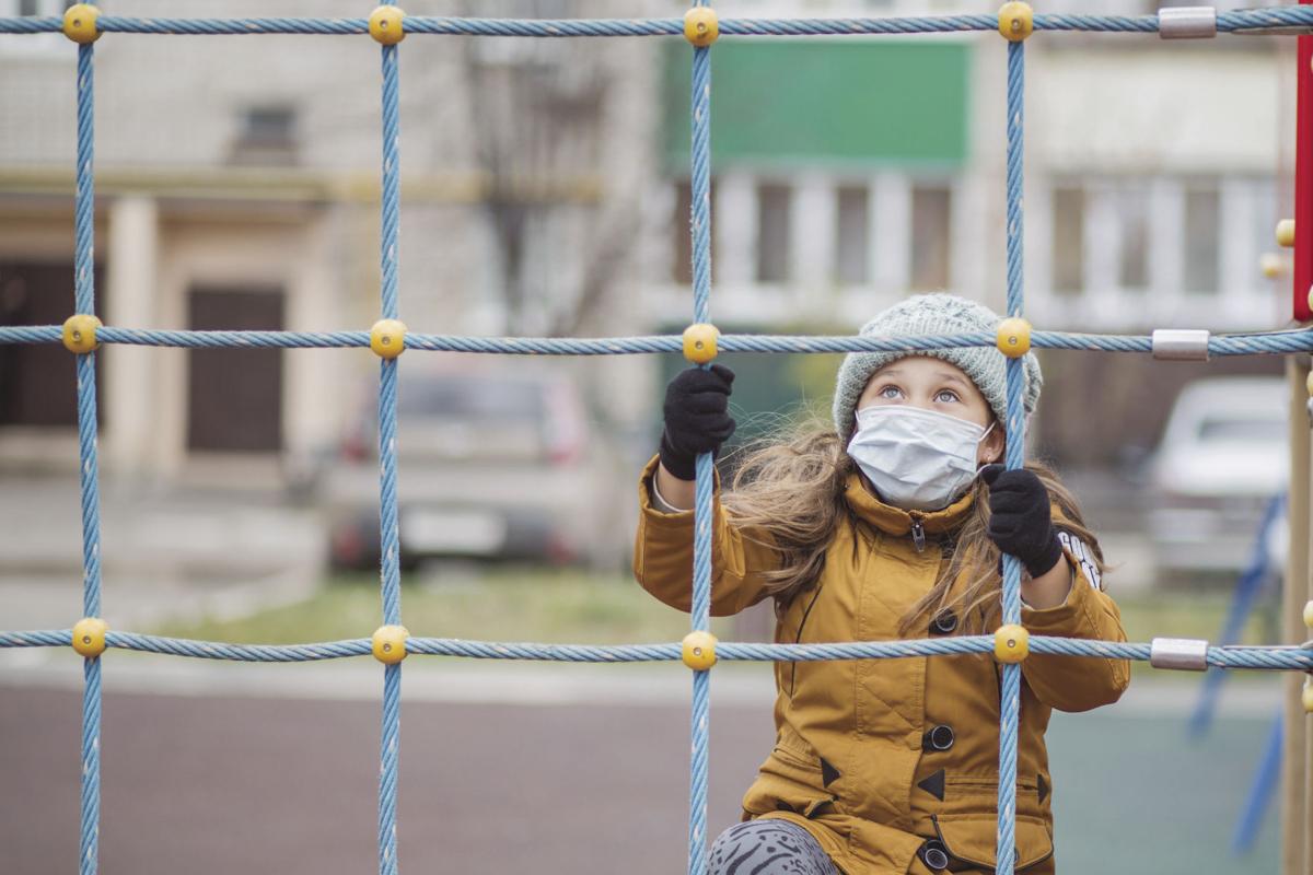 Little girl in medical mask. At atumn playground