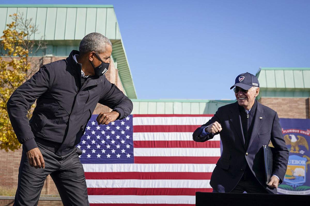 Former U.S. President Barack Obama and Democratic presidential nominee Joe Biden greet each other with a socially distant "air" elbow bump at the end of a drive-in campaign rally at Northwestern High School on Oct. 31, 2020 in Flint, Michigan.