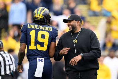 Michigan head coach Sherrone Moore, right, will have freshman quarterback Bryce Underwood in the mix this season, though the Wolverines say the competition at the position remains open.