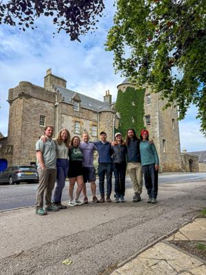 A group of happy travelers, from left, Elijah Hawley, Sarah Holm, Mara Díaz, Owen Osterling, Patrick Connolly, Karissa Bellile, Matt Starkey and Leigh Bacho, congregate outside the Dornoch Castle Hotel in the Highlands of Scotland on July 3, 2026.